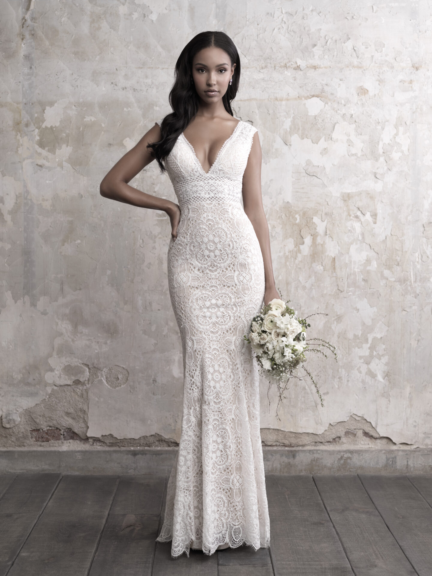 A woman in white dress holding flowers and posing for the camera.