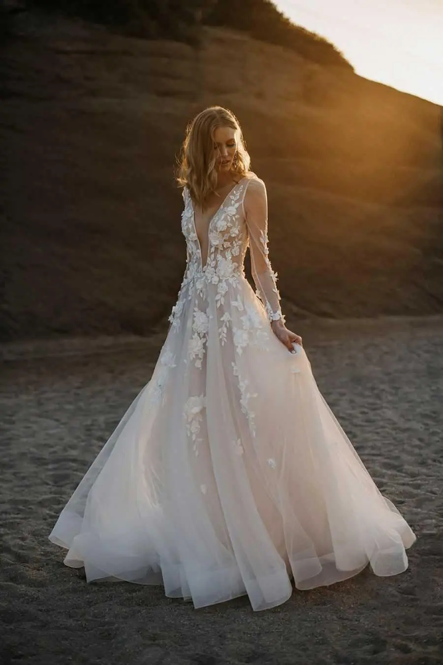 A woman in a white dress standing on the beach.