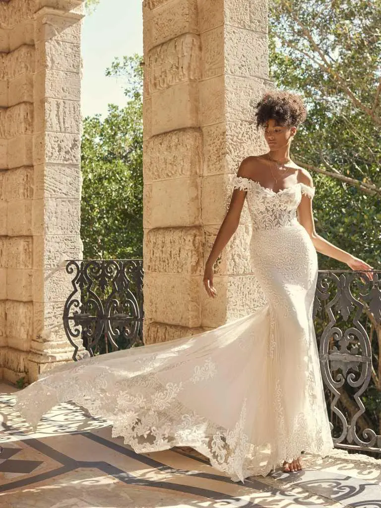 A woman in a white dress standing next to pillars.