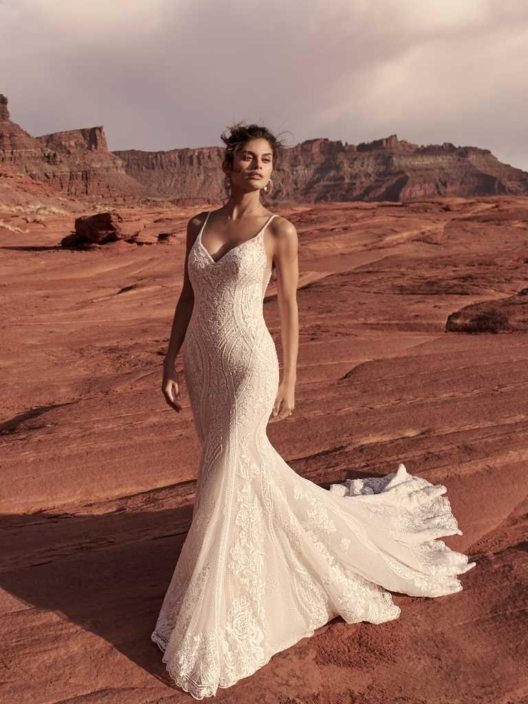 A woman in a white dress standing on top of a hill.