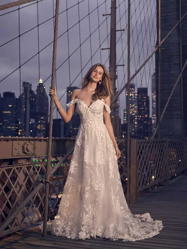 A woman in a white dress standing on top of a bridge.