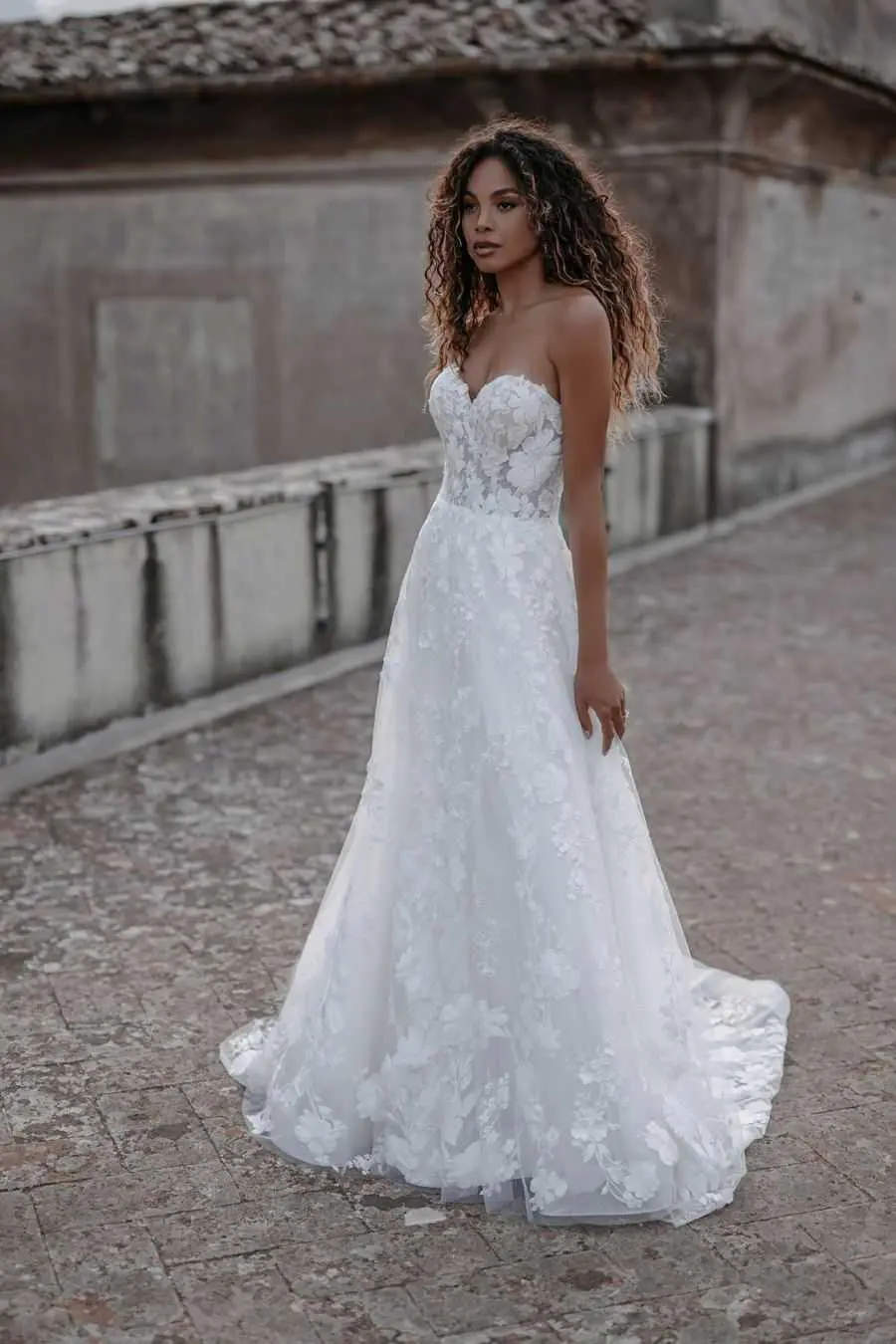 A woman in a white dress standing on the street.