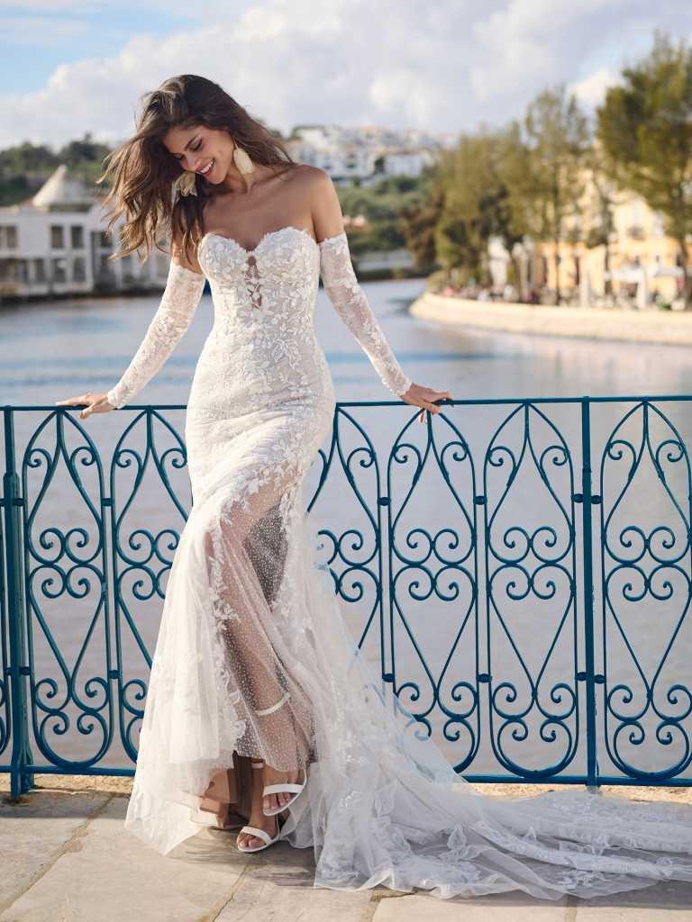 A woman in a white dress standing on the side of a bridge.