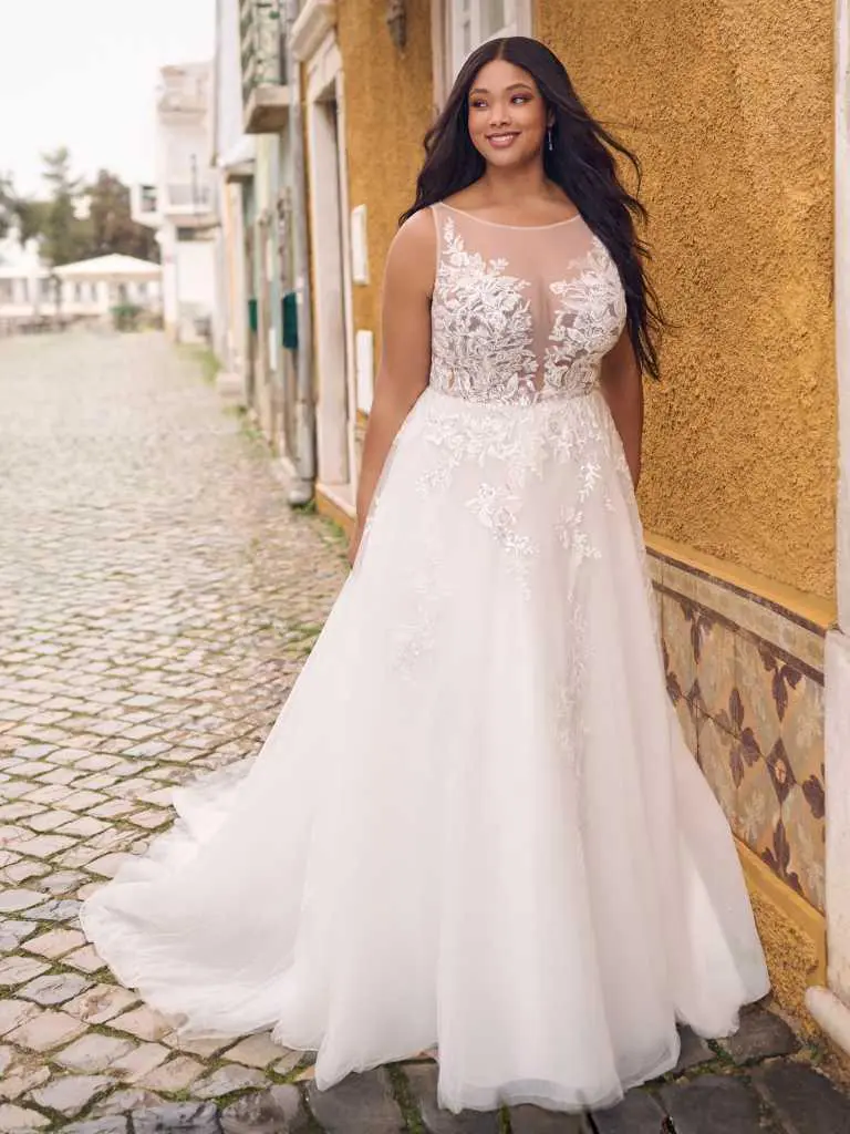 A woman in a white dress standing on the sidewalk.