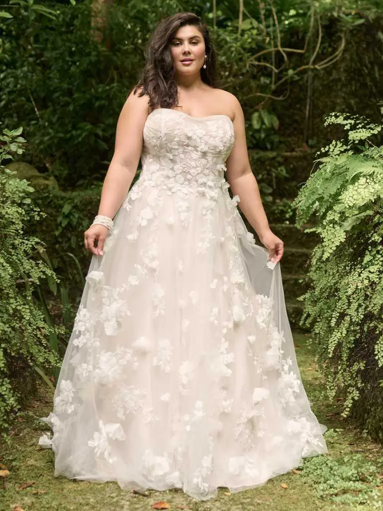 A woman in a white dress standing next to trees.