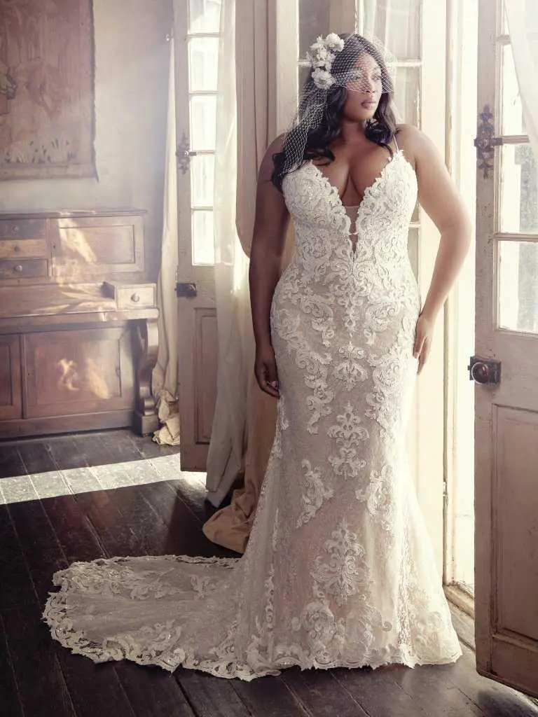 A woman in a white dress standing next to a window.