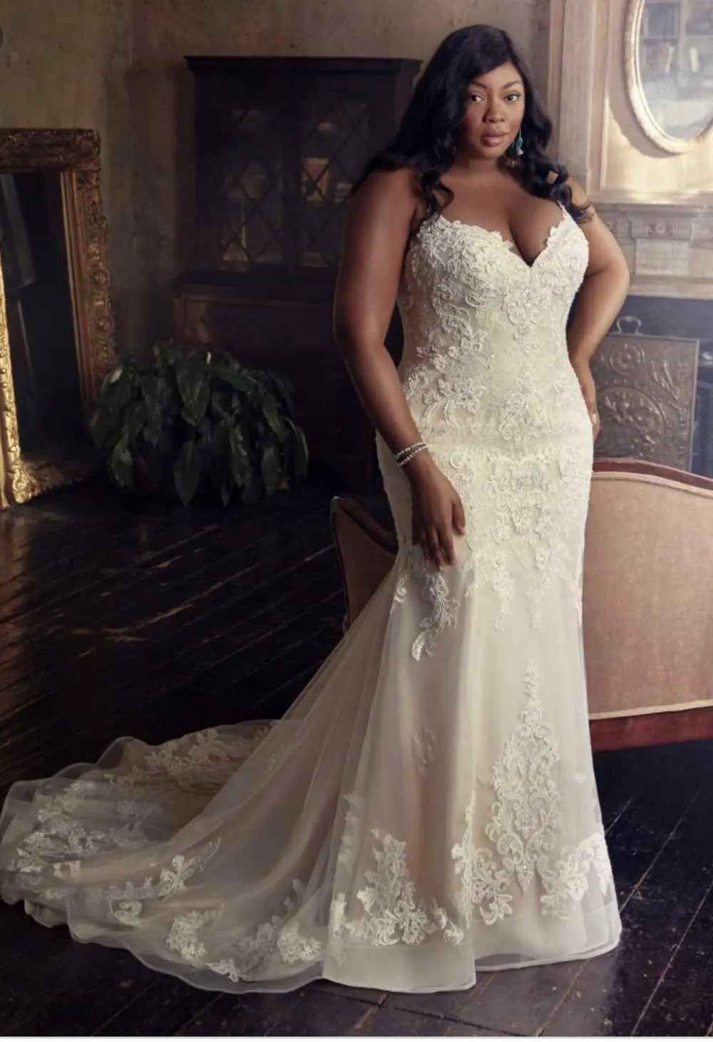 A woman in a white dress standing next to a fireplace.