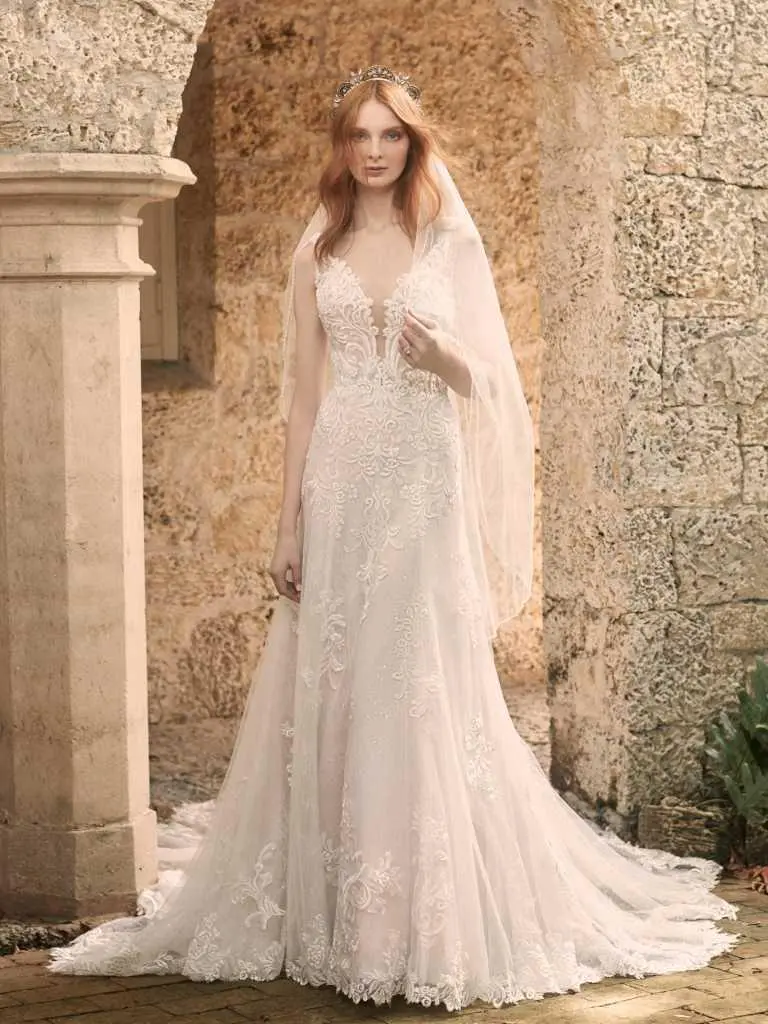 A woman in a white dress standing next to a stone wall.