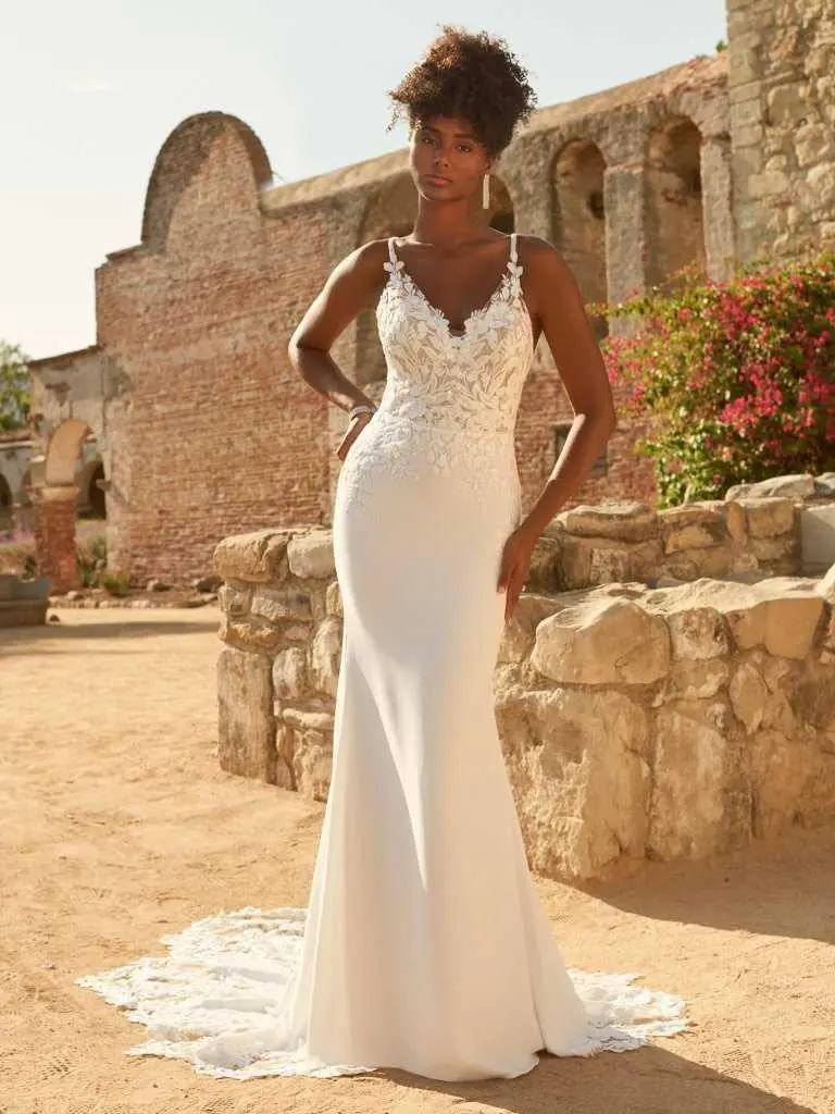 A woman in white dress standing on top of a rock wall.