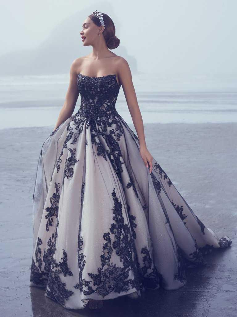 A woman in a black and white dress standing on the beach.