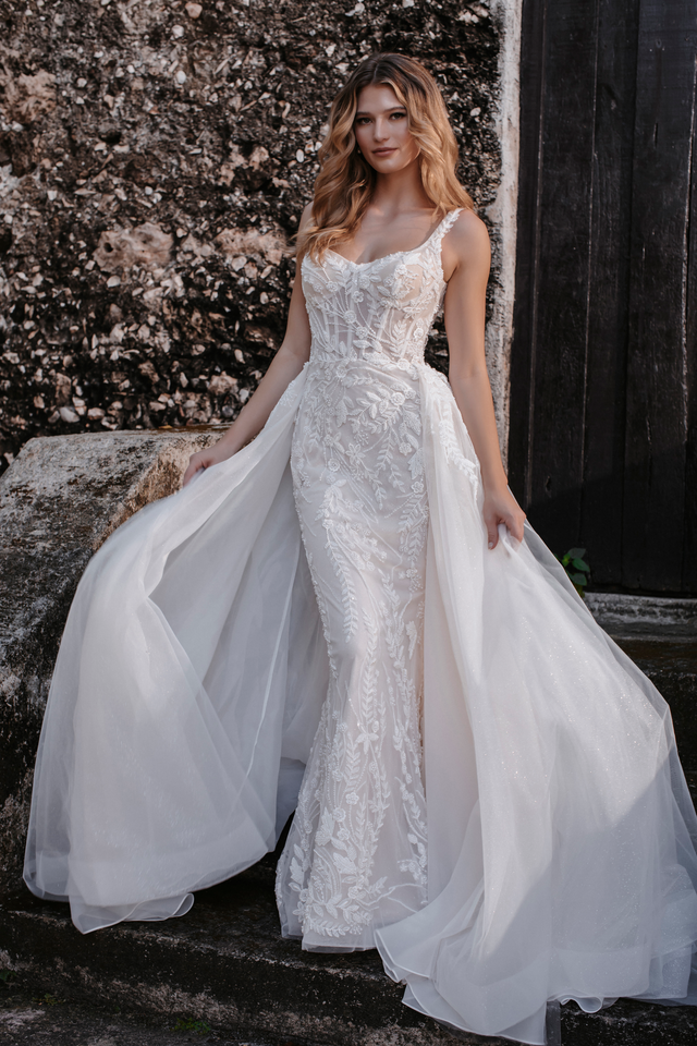 A woman in a wedding dress standing next to a stone wall.