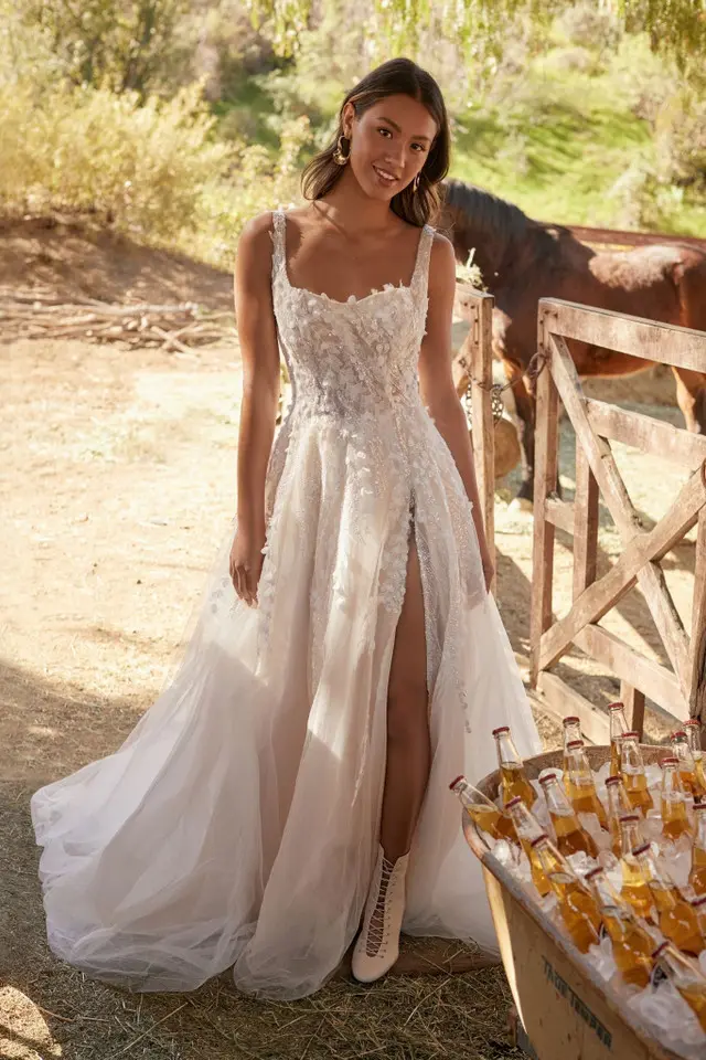 A woman in a wedding dress standing next to a horse.