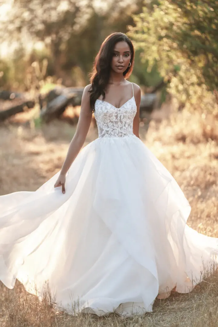 A woman in a white dress standing on top of a dry grass field.