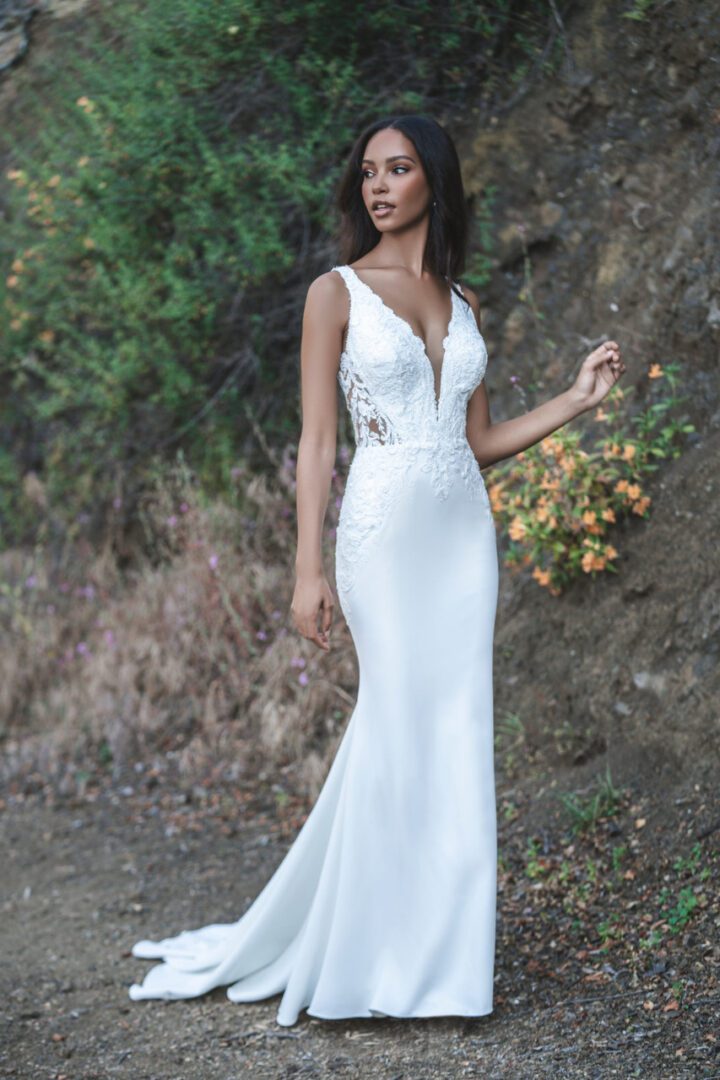 A woman in white dress standing next to a tree.