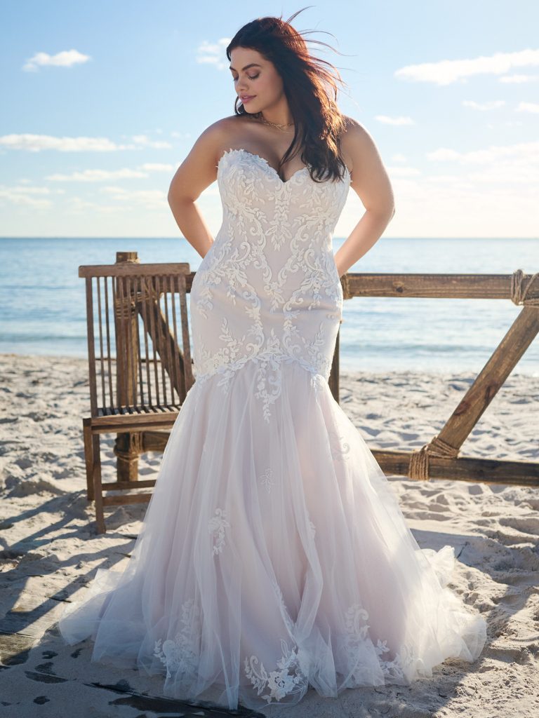 A woman in a white dress standing on the beach.