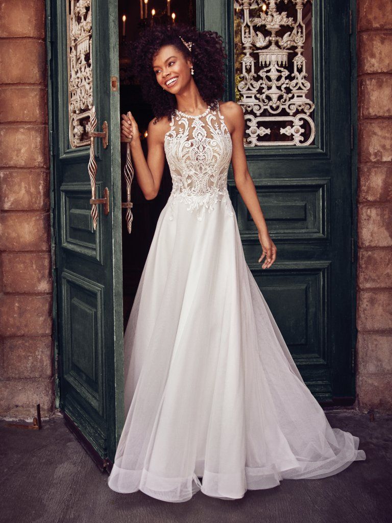 A woman in a white dress standing next to a door.