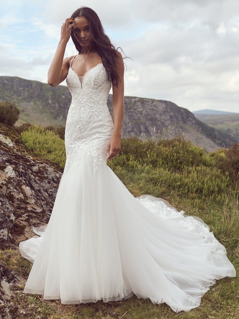 A woman in a white dress standing on top of a hill.