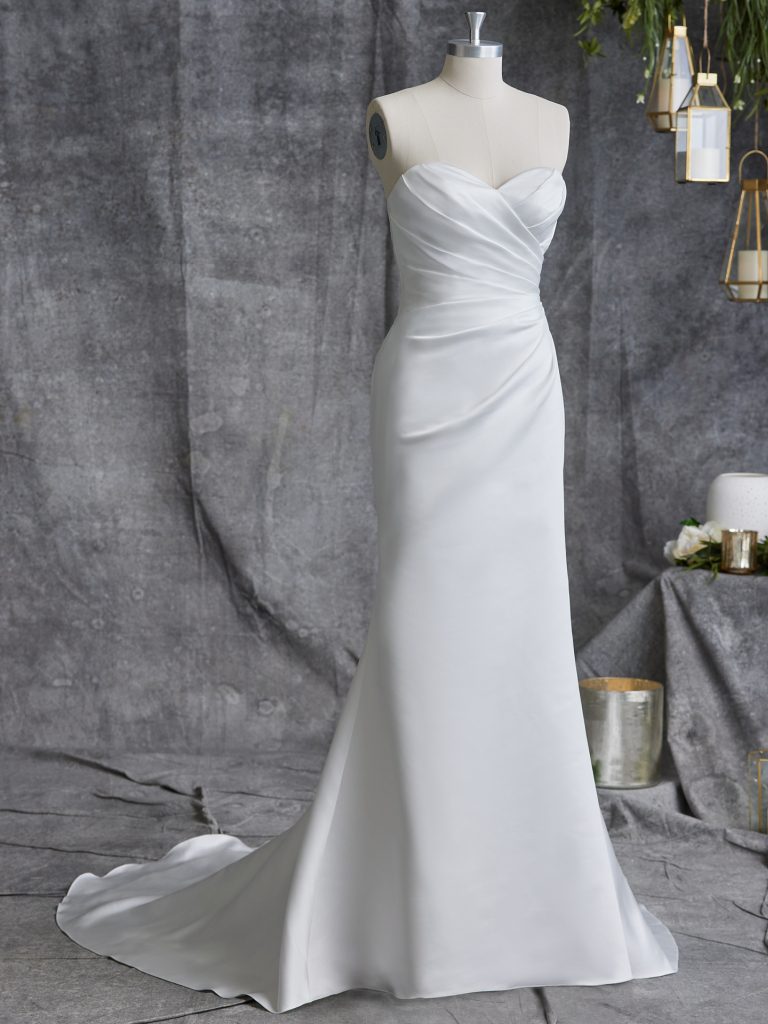 A white dress is on display in front of a gray background.