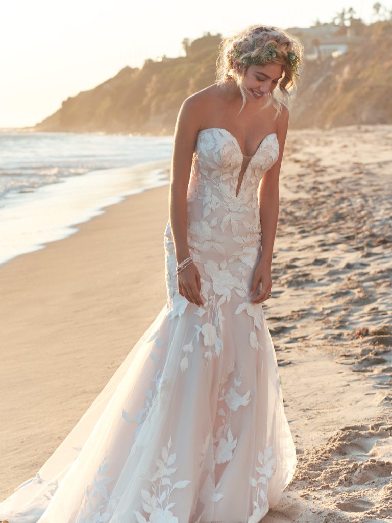 A woman in a white dress standing on the beach.