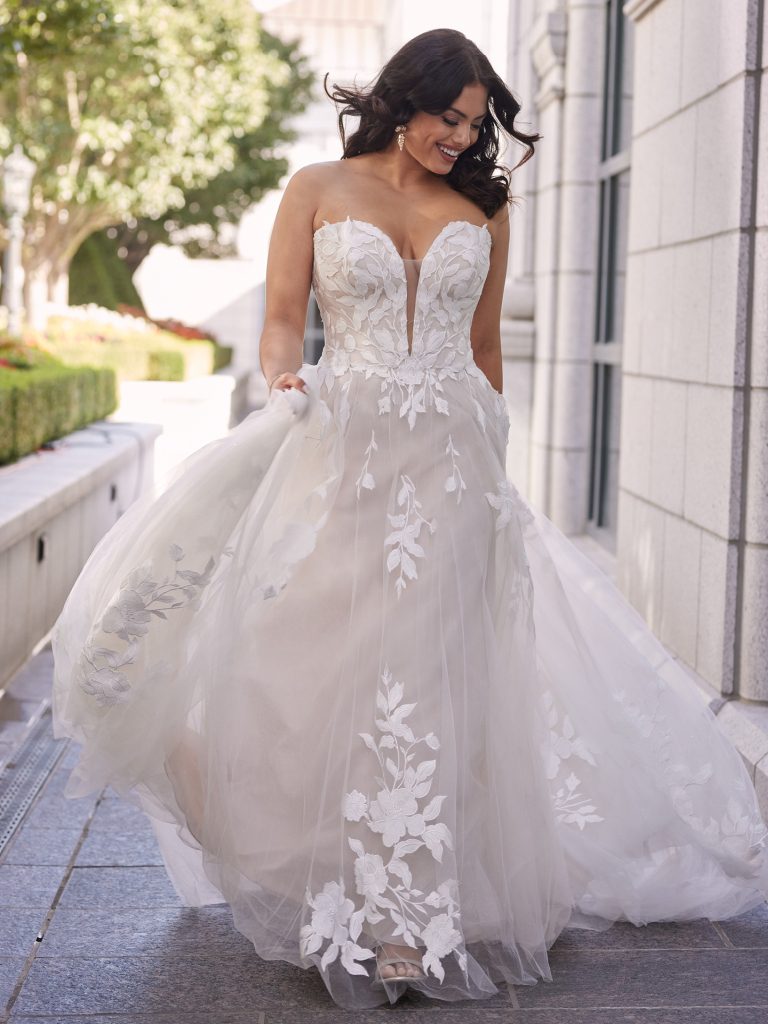 A woman in a white dress standing on the sidewalk.