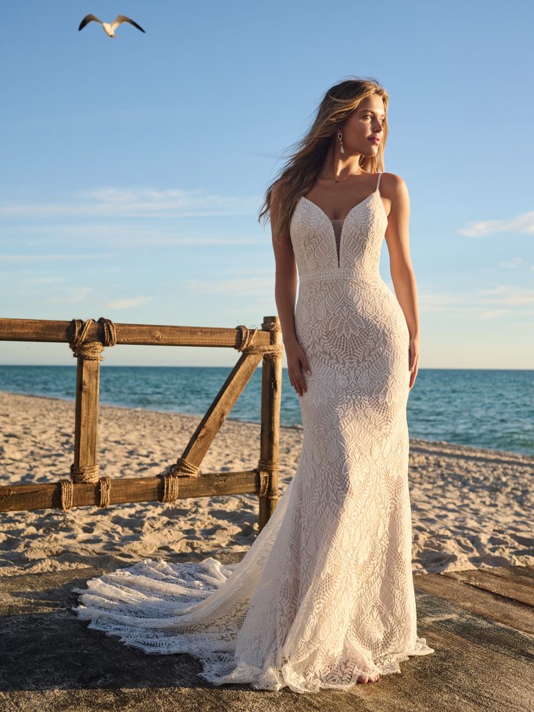 A woman in a white dress standing on the beach.