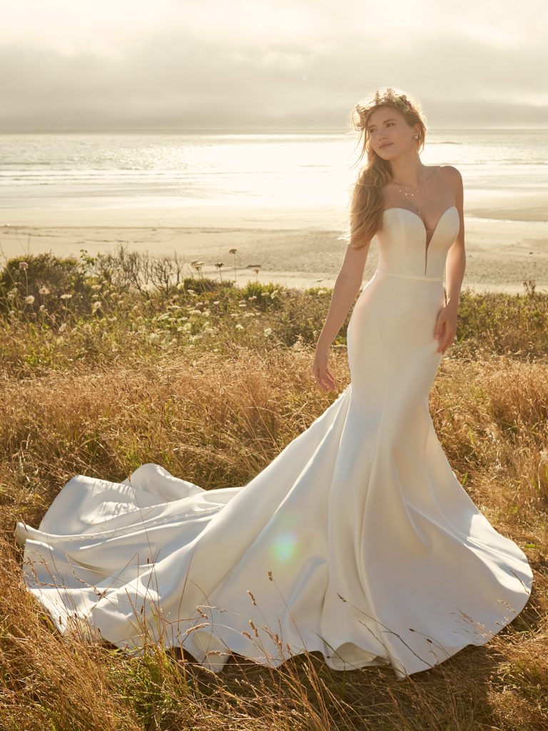 A woman in a white dress standing on top of a hill.