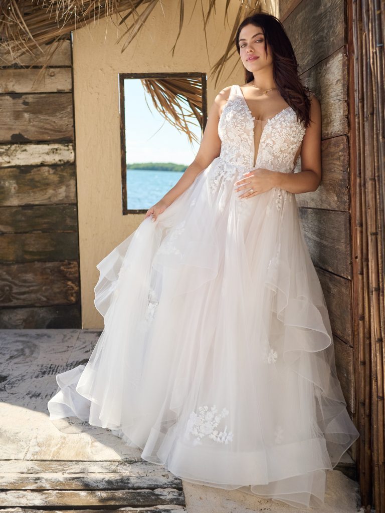 A woman in a white dress leaning against a wall